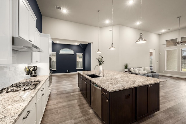 kitchen with sink, dark brown cabinets, stainless steel appliances, a center island with sink, and decorative light fixtures