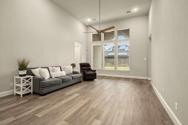 living room with hardwood / wood-style flooring, ceiling fan, and a high ceiling