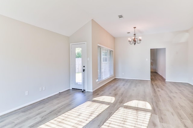 entrance foyer featuring an inviting chandelier, lofted ceiling, and light wood-type flooring