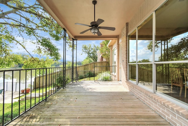 wooden terrace with a water view and ceiling fan