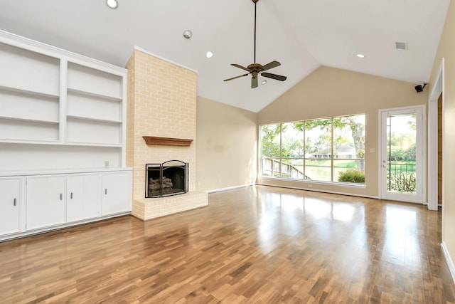 unfurnished living room featuring vaulted ceiling, ceiling fan, light hardwood / wood-style floors, and a brick fireplace