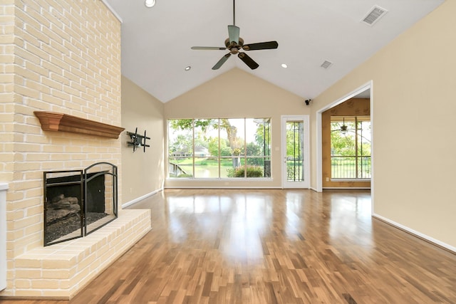 unfurnished living room with hardwood / wood-style flooring, ceiling fan, vaulted ceiling, and a brick fireplace