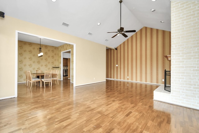 unfurnished living room featuring hardwood / wood-style flooring, ceiling fan, a large fireplace, and high vaulted ceiling