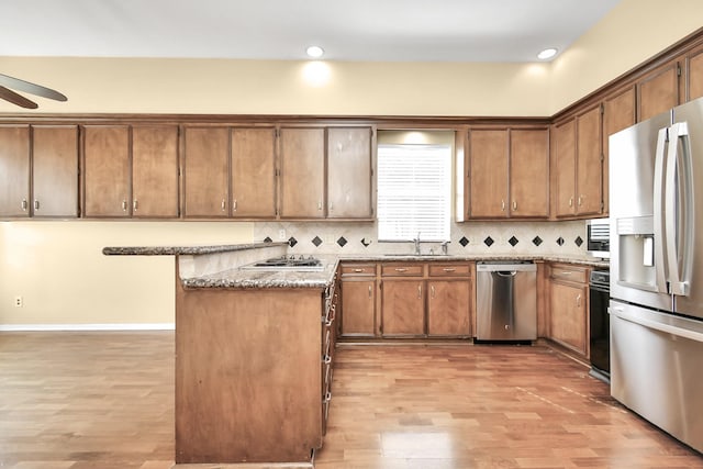 kitchen with sink, light wood-type flooring, appliances with stainless steel finishes, ceiling fan, and decorative backsplash