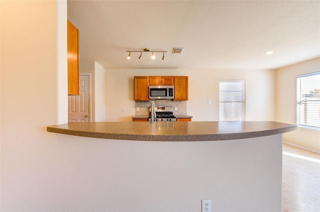 kitchen featuring decorative backsplash, kitchen peninsula, and appliances with stainless steel finishes