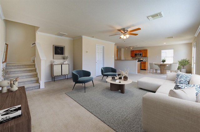 carpeted living room with crown molding and ceiling fan