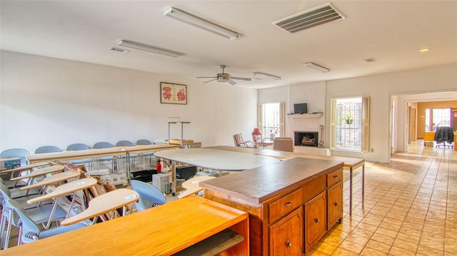 kitchen featuring light tile patterned floors, a fireplace, and ceiling fan