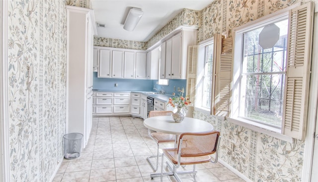 kitchen with white cabinetry, stainless steel dishwasher, sink, and light tile patterned floors