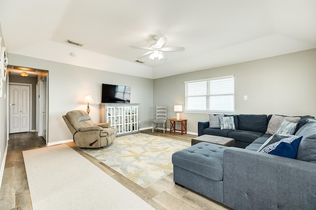 living room featuring a raised ceiling, vaulted ceiling, hardwood / wood-style floors, and ceiling fan