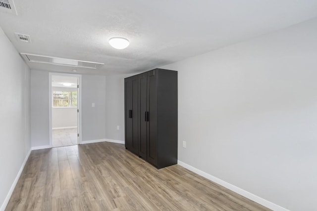 spare room with light hardwood / wood-style flooring and a textured ceiling