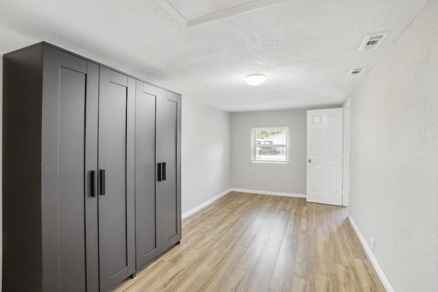 unfurnished bedroom featuring a closet, light hardwood / wood-style floors, and a textured ceiling