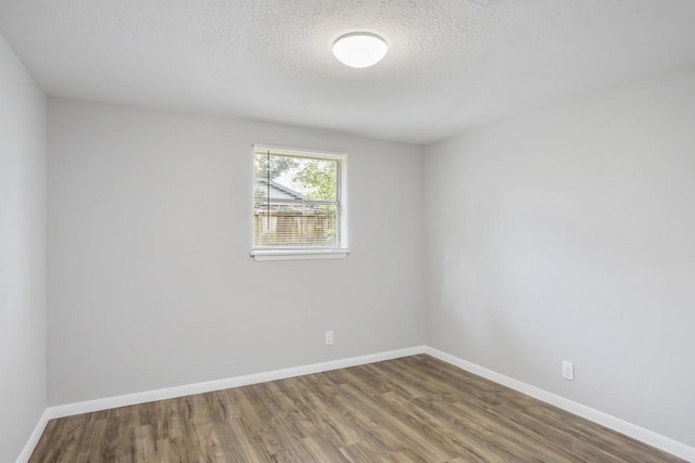 empty room featuring wood-type flooring and a textured ceiling