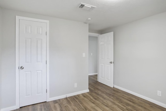 unfurnished bedroom with dark wood-type flooring and a textured ceiling