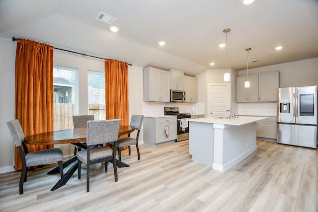 kitchen featuring sink, tasteful backsplash, decorative light fixtures, an island with sink, and stainless steel appliances