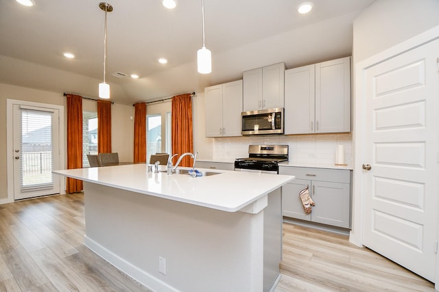 kitchen featuring decorative light fixtures, tasteful backsplash, sink, a kitchen island with sink, and stainless steel appliances