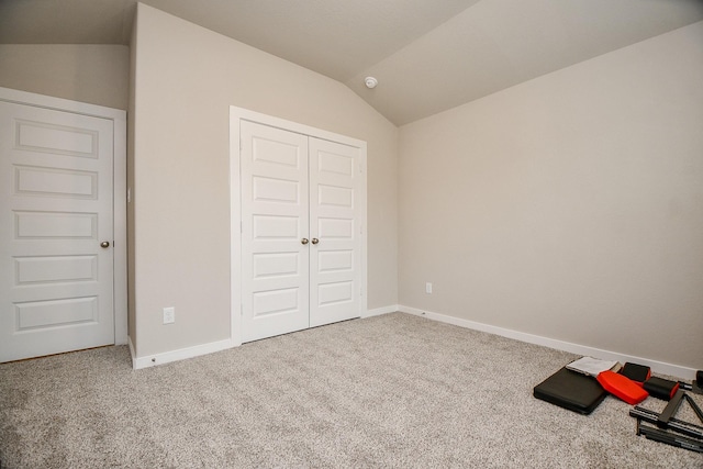 unfurnished bedroom with vaulted ceiling, carpet floors, and a closet