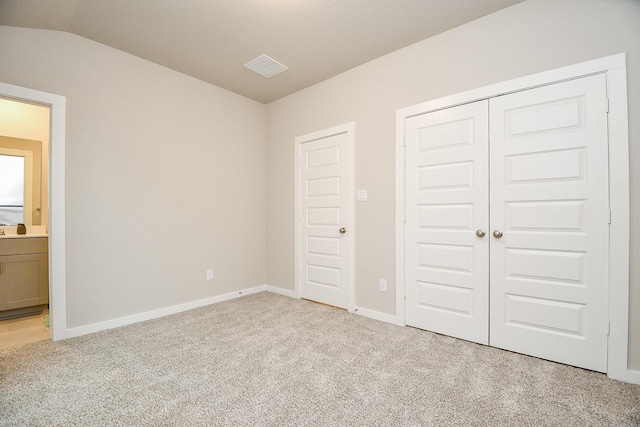 unfurnished bedroom with lofted ceiling, light carpet, and connected bathroom