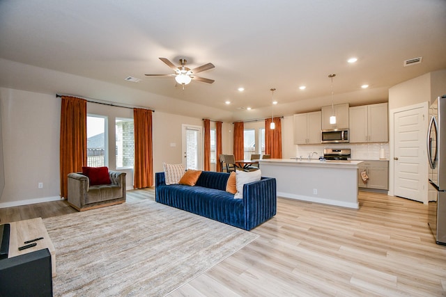 living room featuring ceiling fan and light hardwood / wood-style flooring