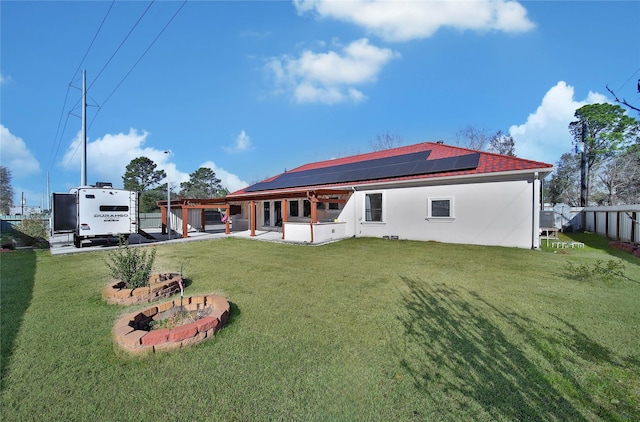 rear view of property with a yard, a patio, and solar panels