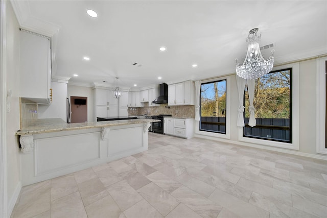 kitchen featuring white cabinetry, black range with gas stovetop, a notable chandelier, kitchen peninsula, and wall chimney exhaust hood