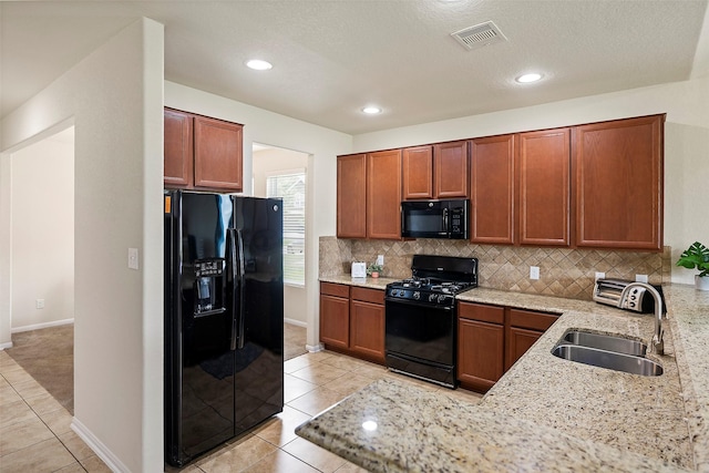 kitchen featuring light tile patterned flooring, sink, black appliances, light stone countertops, and backsplash