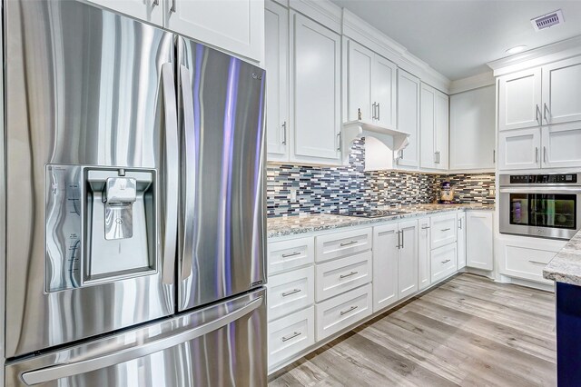 kitchen featuring light hardwood / wood-style flooring, stainless steel appliances, tasteful backsplash, light stone countertops, and white cabinets