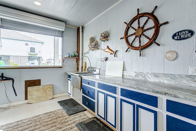 kitchen featuring crown molding, light stone countertops, and blue cabinetry