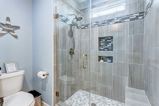 bathroom with a shower with door and toilet