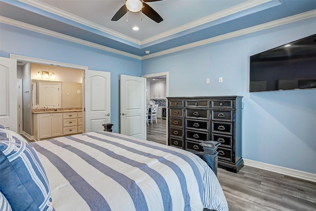 bedroom with ensuite bathroom, dark hardwood / wood-style flooring, ornamental molding, ceiling fan, and a tray ceiling