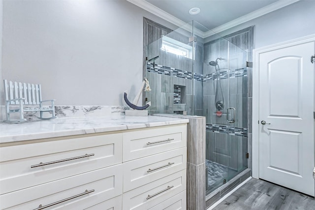 bathroom with vanity, ornamental molding, wood-type flooring, and a shower with shower door