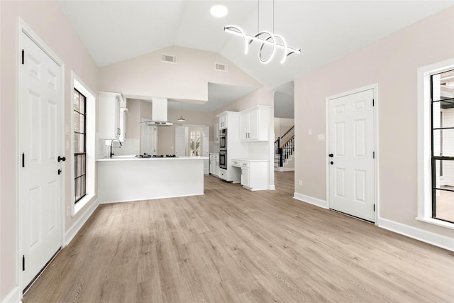 unfurnished living room featuring lofted ceiling, a wealth of natural light, and light hardwood / wood-style floors