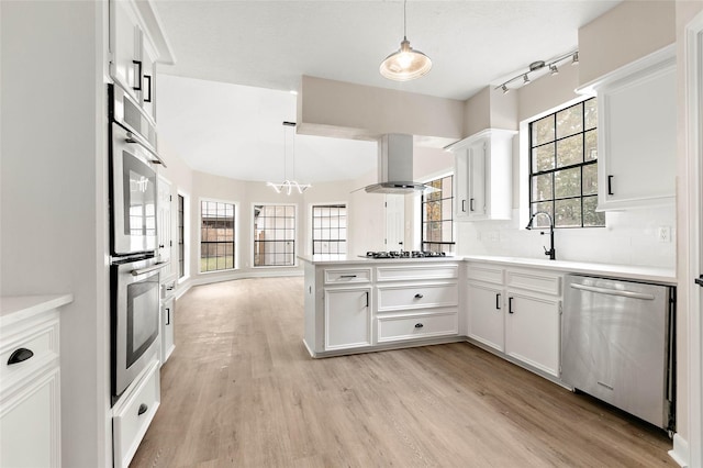 kitchen with white cabinetry, appliances with stainless steel finishes, decorative light fixtures, and island range hood