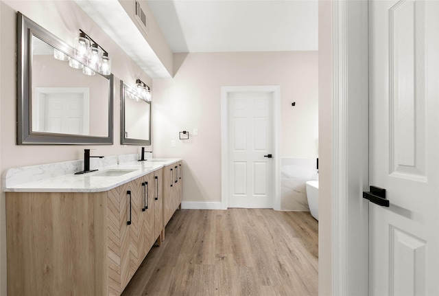 bathroom featuring vanity, hardwood / wood-style floors, and a tub to relax in