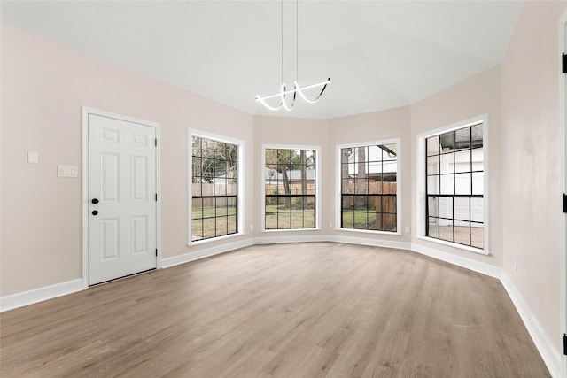 unfurnished dining area with an inviting chandelier and light wood-type flooring