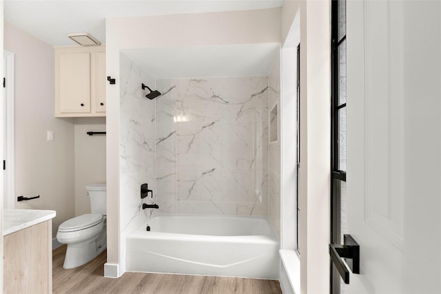 full bathroom featuring hardwood / wood-style flooring, tiled shower / bath, vanity, and toilet