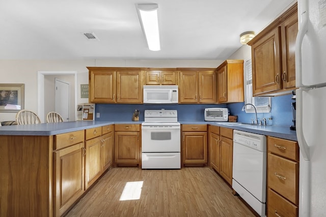 kitchen featuring sink, white appliances, light hardwood / wood-style flooring, and kitchen peninsula