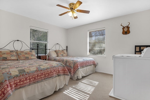 bedroom with washer / dryer, light colored carpet, and ceiling fan