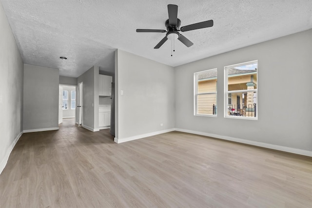 unfurnished living room with ceiling fan, light hardwood / wood-style floors, and a textured ceiling