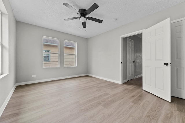 unfurnished room with ceiling fan, a wealth of natural light, a textured ceiling, and light wood-type flooring