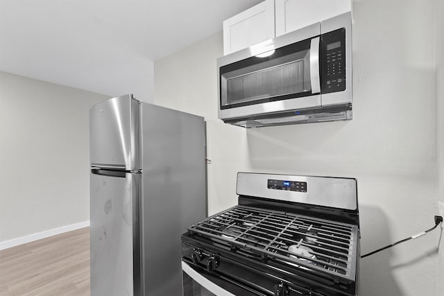 kitchen with appliances with stainless steel finishes, light hardwood / wood-style floors, and white cabinets