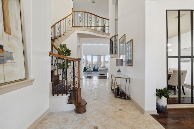 entrance foyer with light tile patterned floors and a towering ceiling