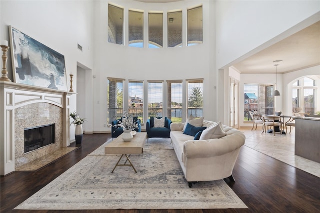 living room featuring crown molding, dark wood-type flooring, and a premium fireplace