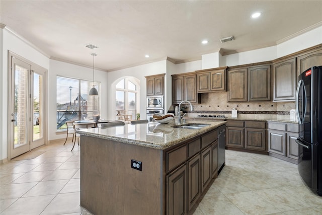 kitchen featuring sink, appliances with stainless steel finishes, light stone countertops, an island with sink, and decorative light fixtures