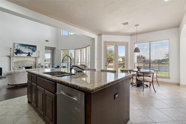 kitchen with sink, light stone counters, decorative light fixtures, light tile patterned floors, and an island with sink