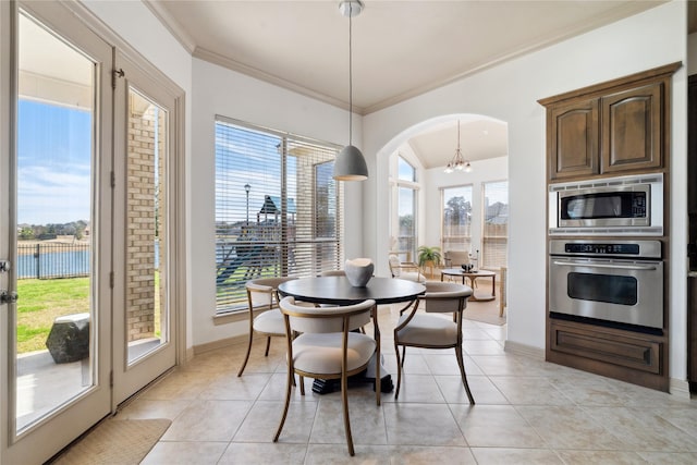 tiled dining room with crown molding, a water view, and a chandelier