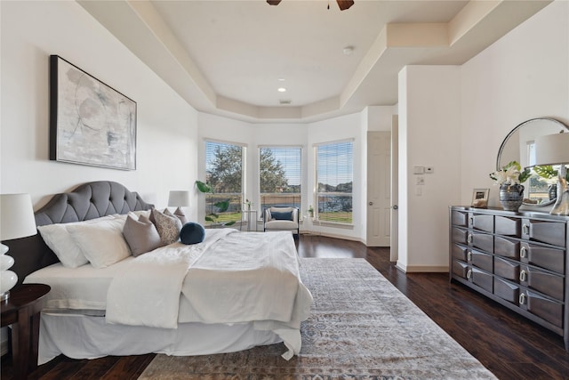 bedroom featuring dark hardwood / wood-style floors, ceiling fan, and a tray ceiling