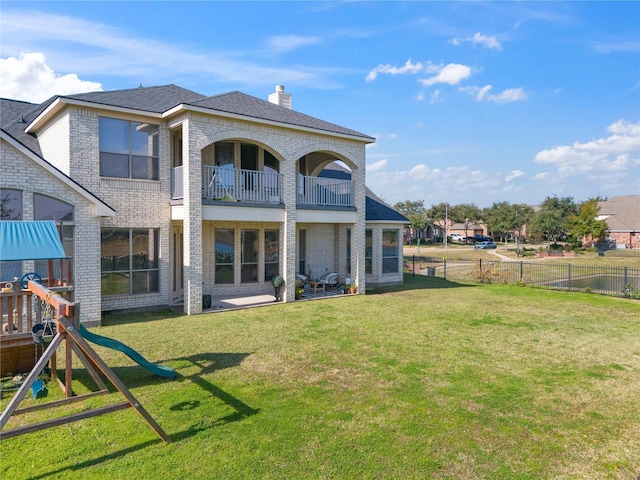 rear view of property featuring a playground and a lawn