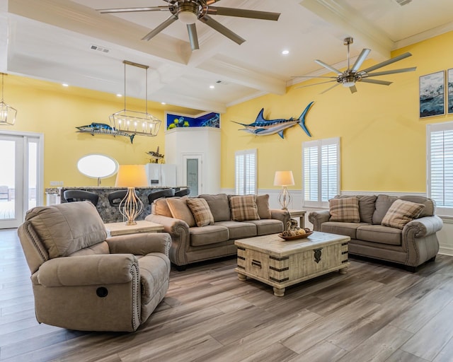 living room featuring crown molding, hardwood / wood-style floors, beam ceiling, and plenty of natural light