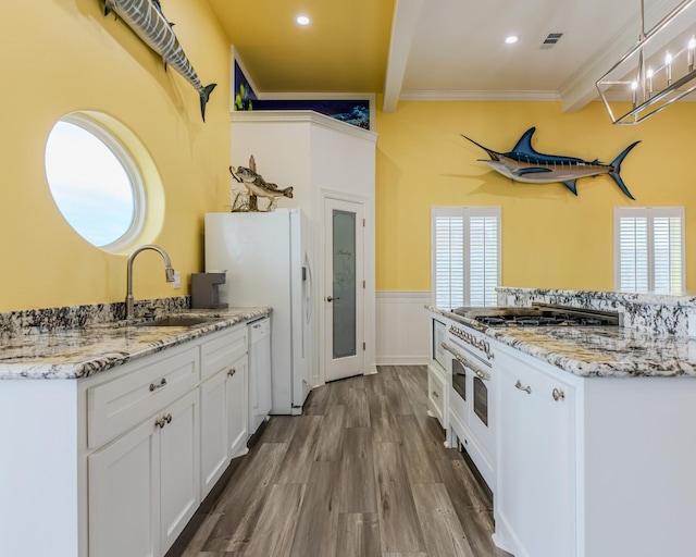 kitchen with sink, white cabinetry, wood-type flooring, white appliances, and beam ceiling