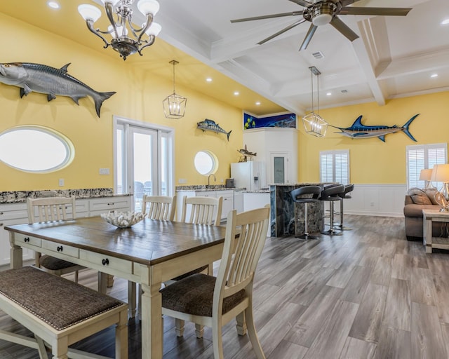 dining room with crown molding, beam ceiling, coffered ceiling, ceiling fan with notable chandelier, and light wood-type flooring